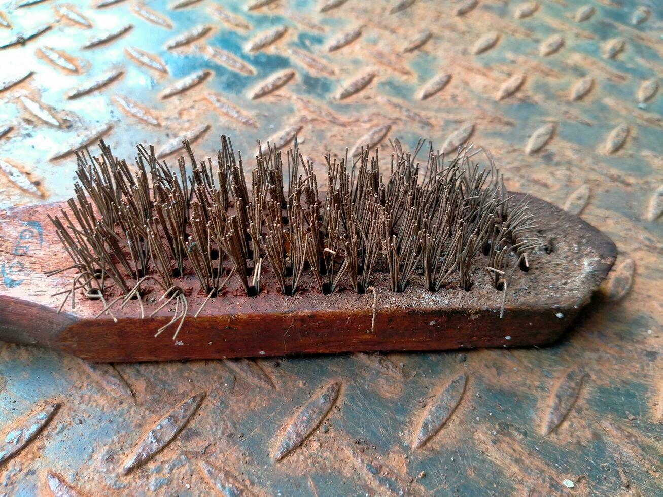 Rustic old Steel wire brush tool on a corroded iron textured background. Tools to clean metal from corrosion photo