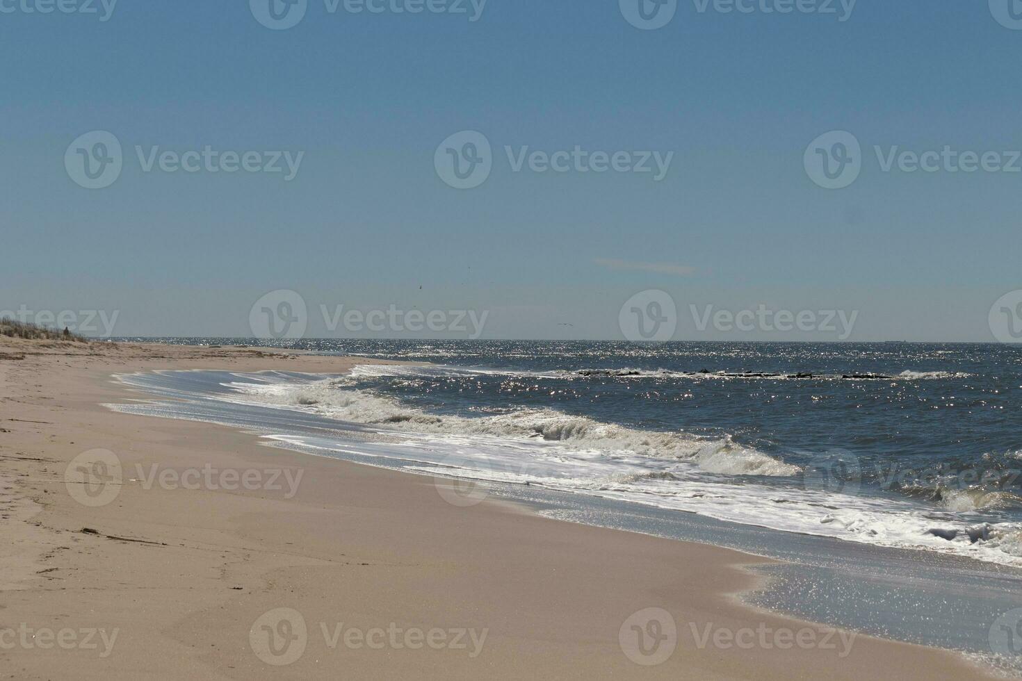 esta hermosa playa imagen estaba tomado a capa mayo nuevo jersey. eso muestra el olas ondulación dentro el apuntalar y el bonito marrón arena. el azul cielo con el pequeño poco de nube cobertura agrega a este. foto