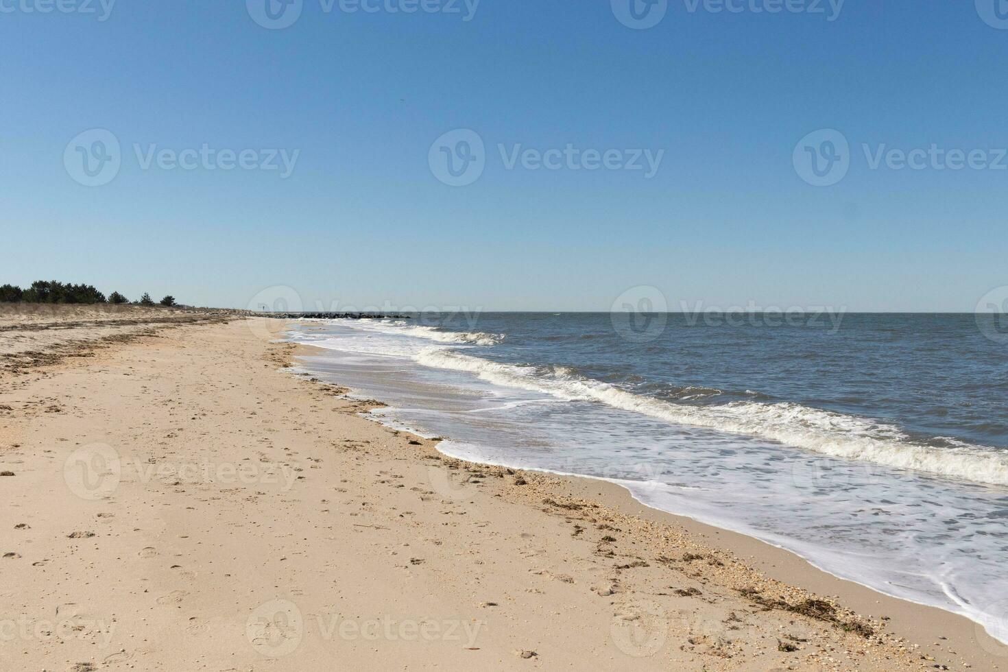 I loved the look of this beach scene as the waves crashed in. The pretty look of the whitecapped surd rushing in to the shore. The sand showing different tone to where the water once was. photo