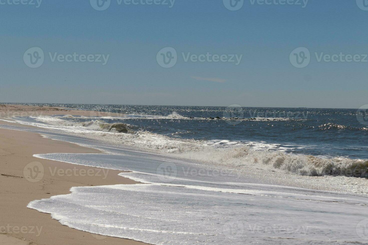 I loved the look of this beach scene as the waves crashed in. The pretty look of the whitecapped surf rushing in to the shore. The sand showing a different tone to where the water once was. photo