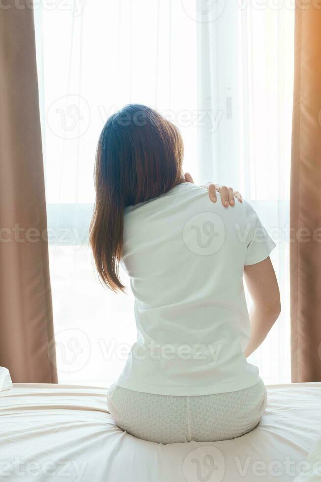 Woman having Shoulder and Neck pain during sitting on bed at home. Muscle painful due to Myofascial pain syndrome and Fibromyalgia, rheumatism, Scapular pain, Cervical Spine. Waking and Health concept photo