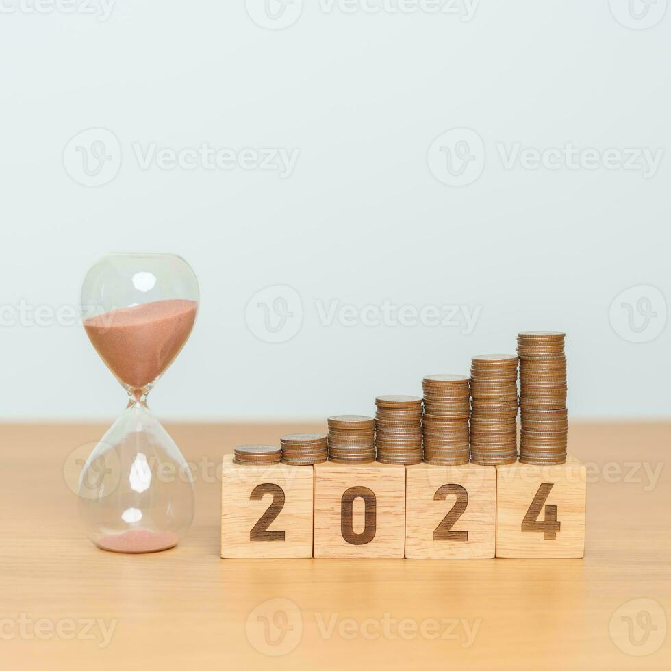 Happy New Year with sandglass and flipping 2023 change to 2024 block. Resolution, Goals, Plan, Action, Money Saving, Retirement fund, Pension, Investment and Financial concept photo