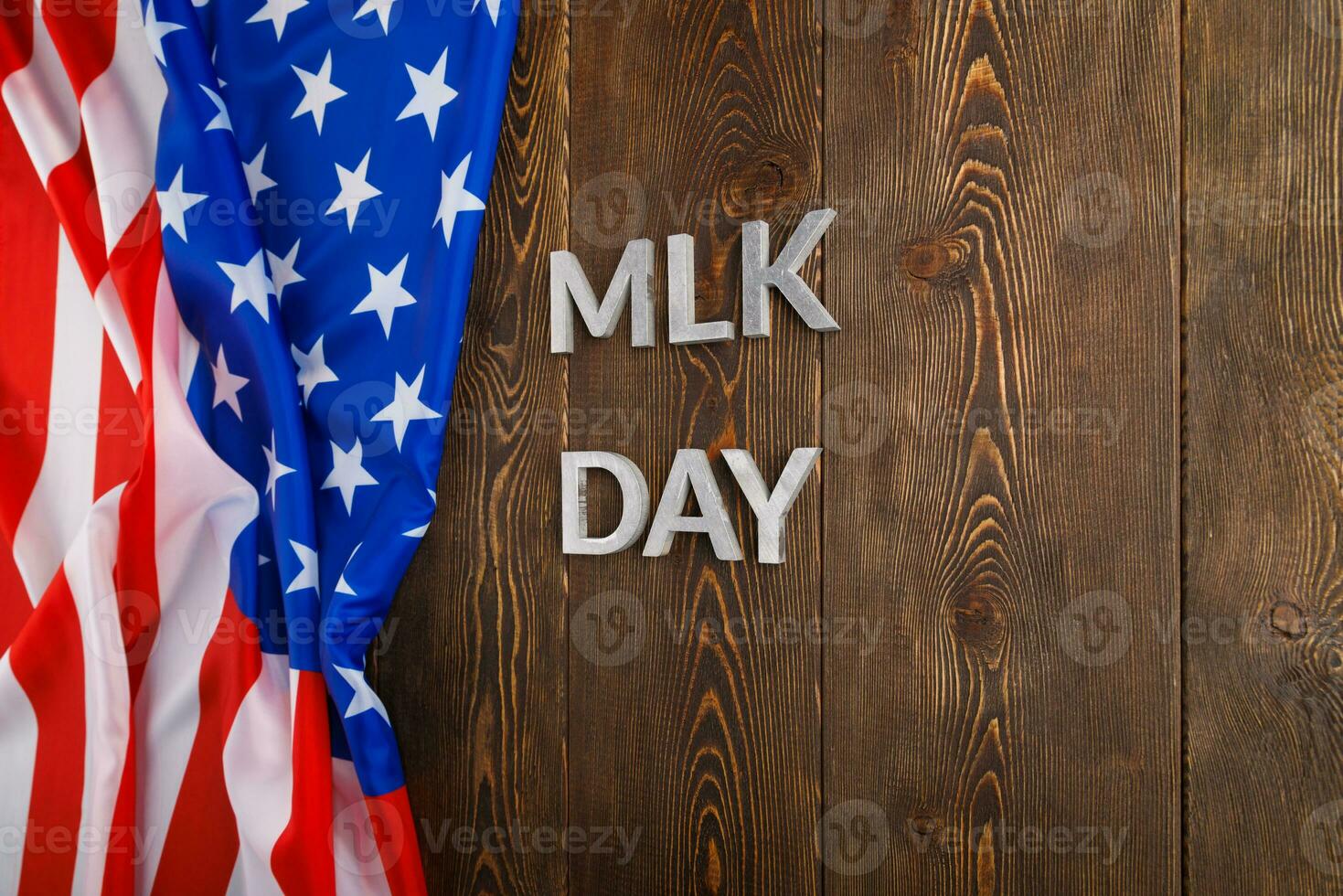 the word MLK day laid with silver metal letters on wooden surface with crumpled USA flag at left side photo