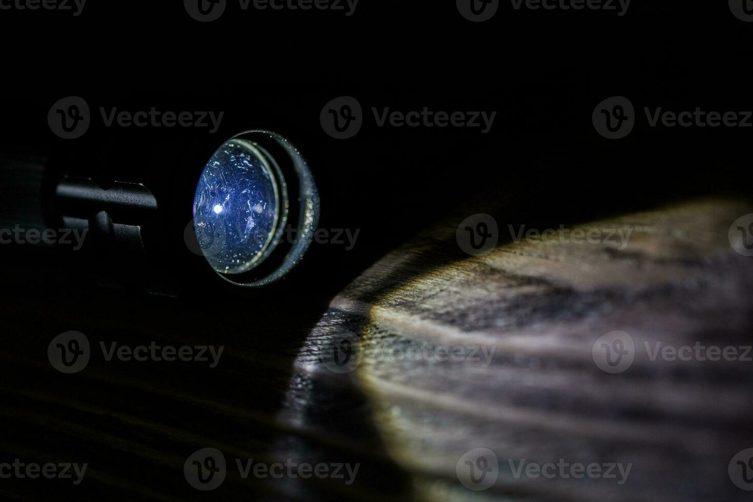 black led operational flashlight on rough wooden surface - closeup with selective focus photo