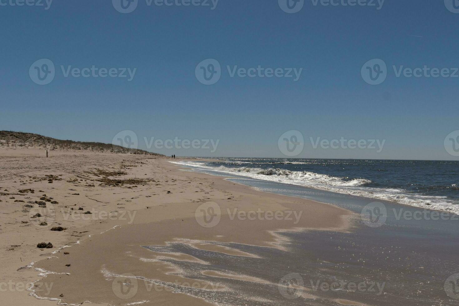 I loved the look of this beach scene as the waves crashed in. The pretty look of the whitecapped surf rushing in to the shore. The sand showing a different tone to where the water once was. photo