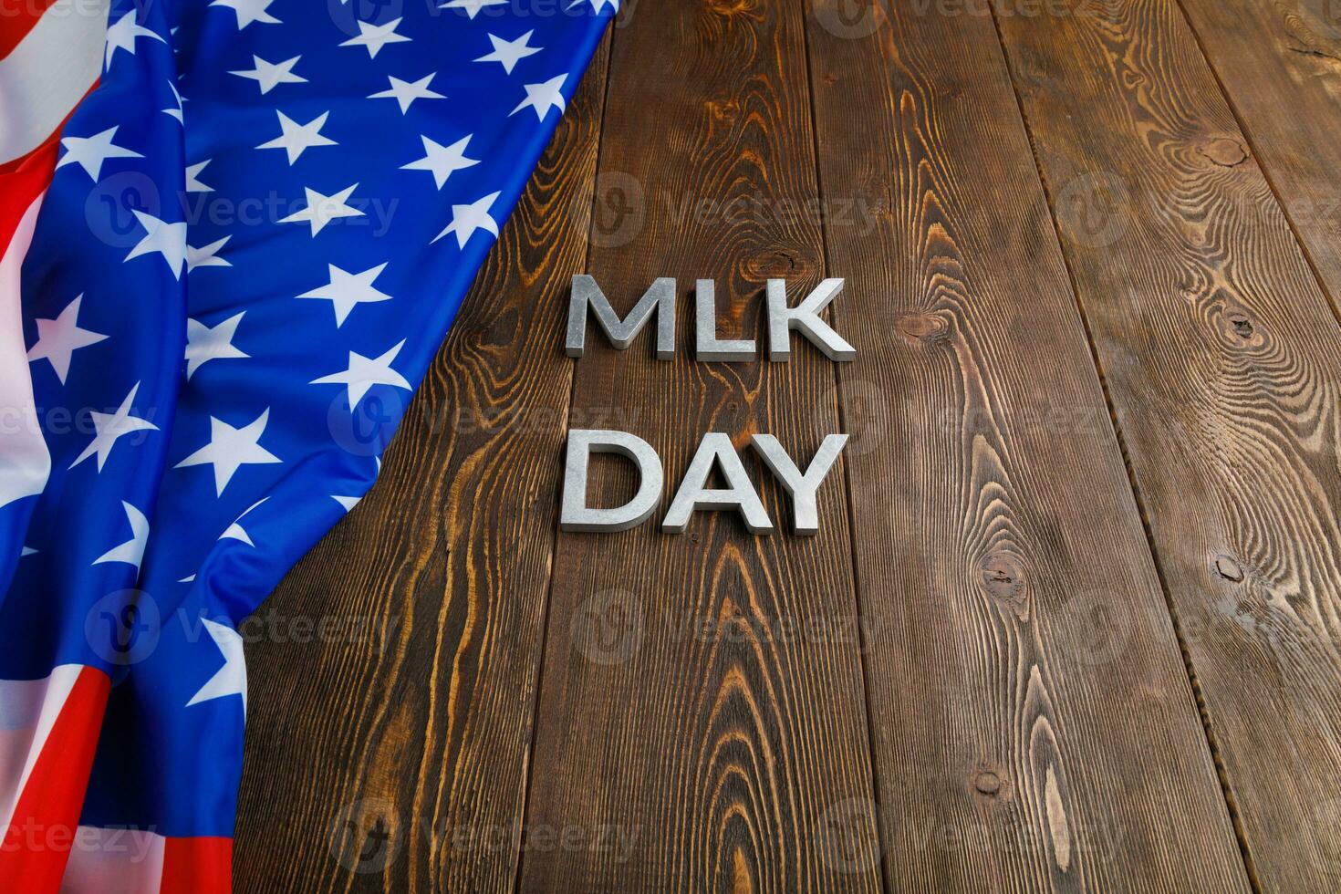 the word MLK day laid with silver metal letters on wooden surface with crumpled USA flag at left side photo