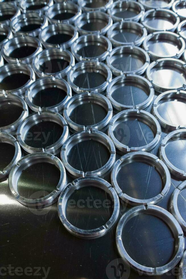 shiny metal rings after turning and milling, silver colored parts on flat steel surface close-up full frame background photo