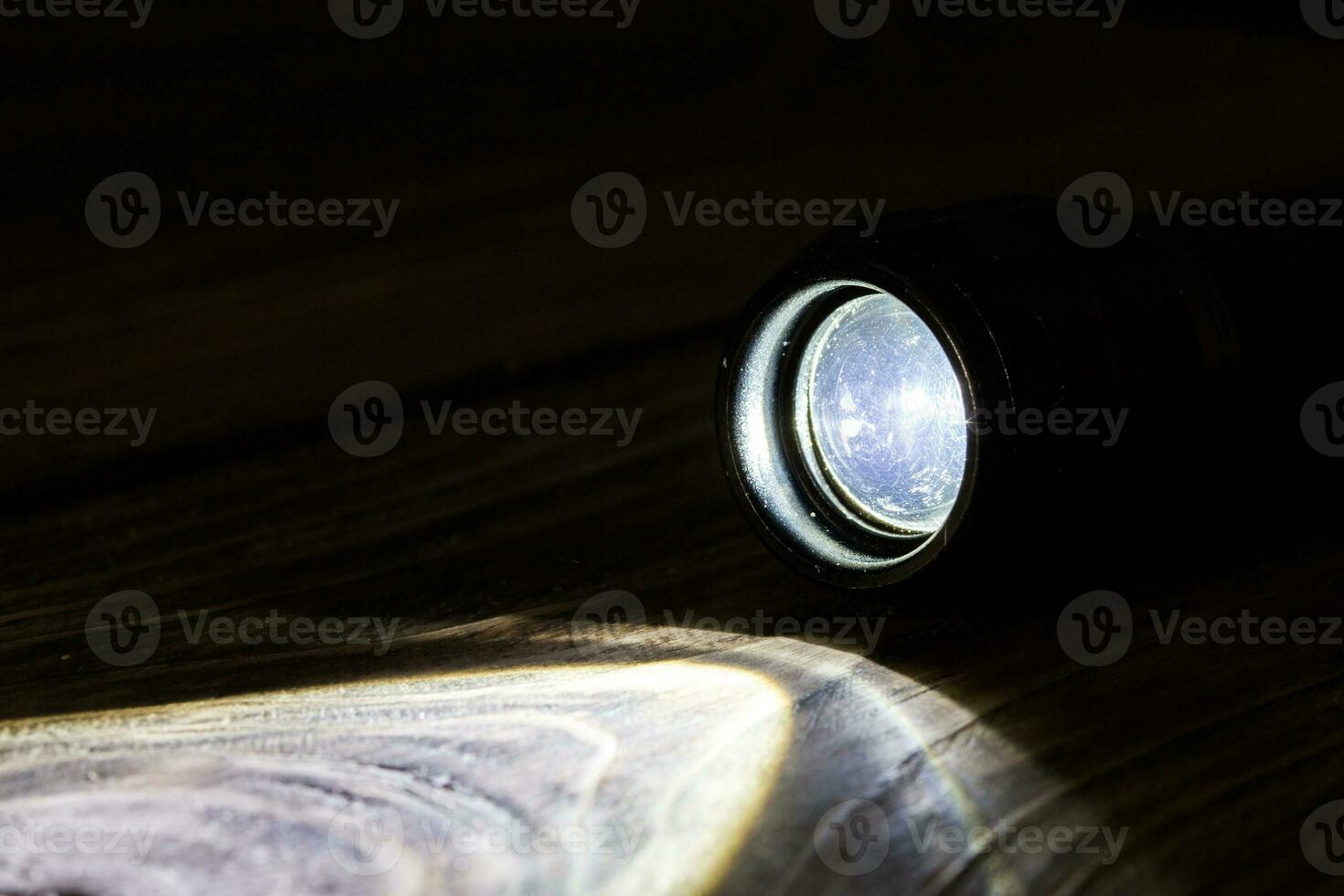 black led operational flashlight on rough wooden surface - closeup with selective focus photo