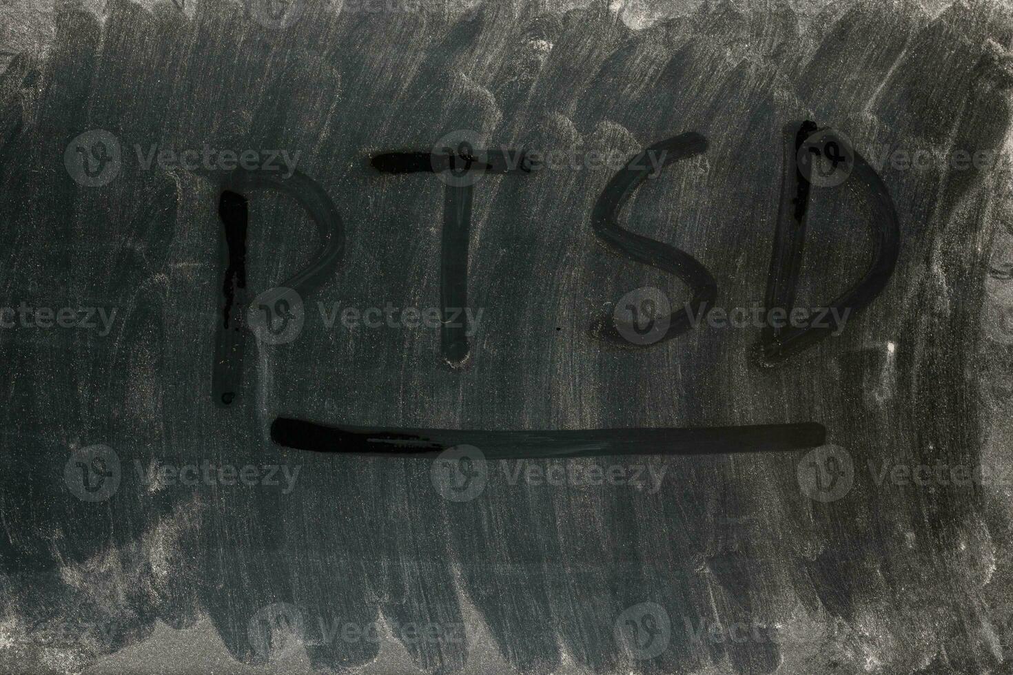 the word PTSD - post traumatic stress disorder handwritten on full frame background and texture of dusty black surface of an old LCD screen photo