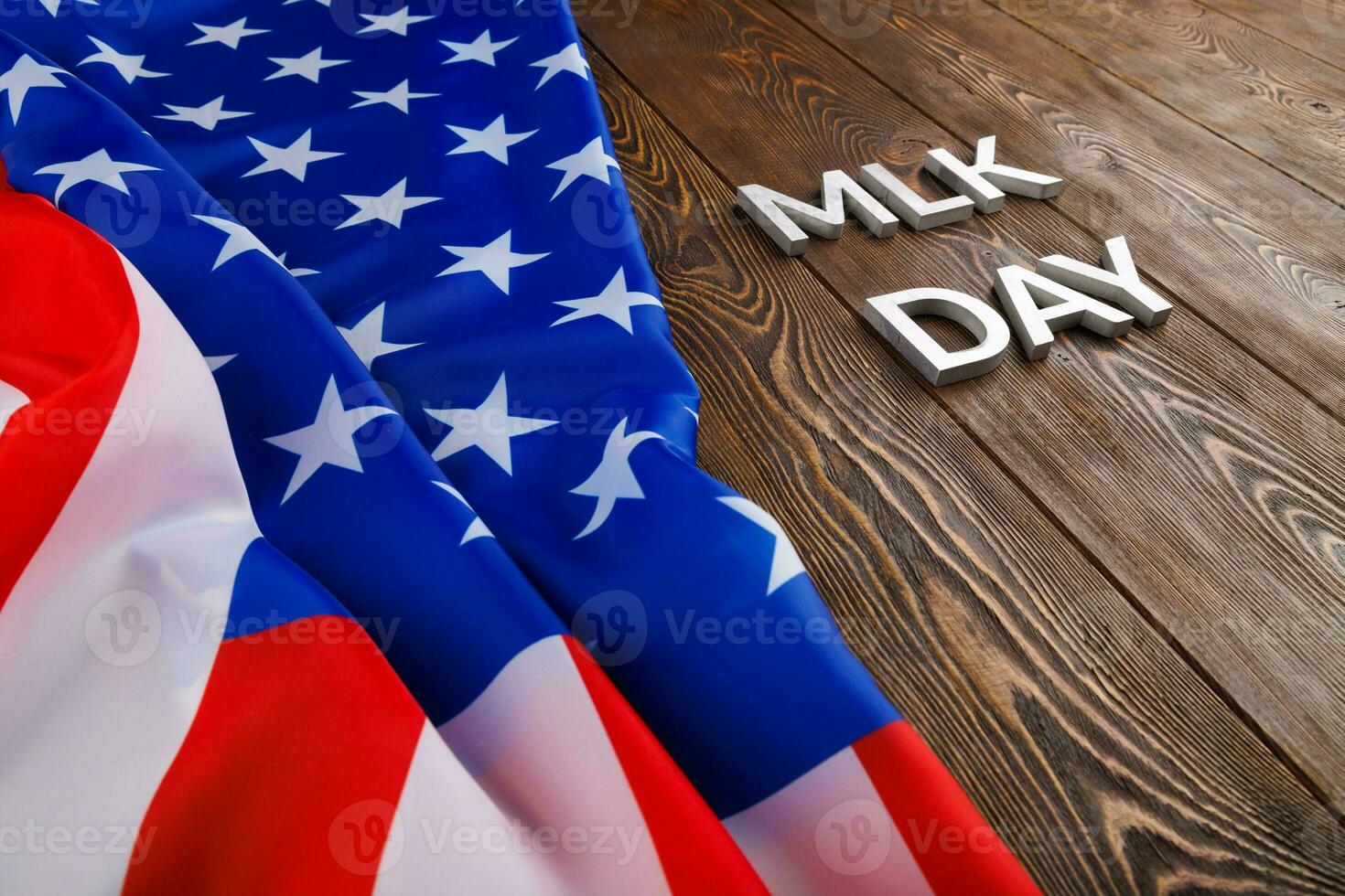 the word MLK day laid with silver metal letters on wooden surface with crumpled USA flag at left side photo