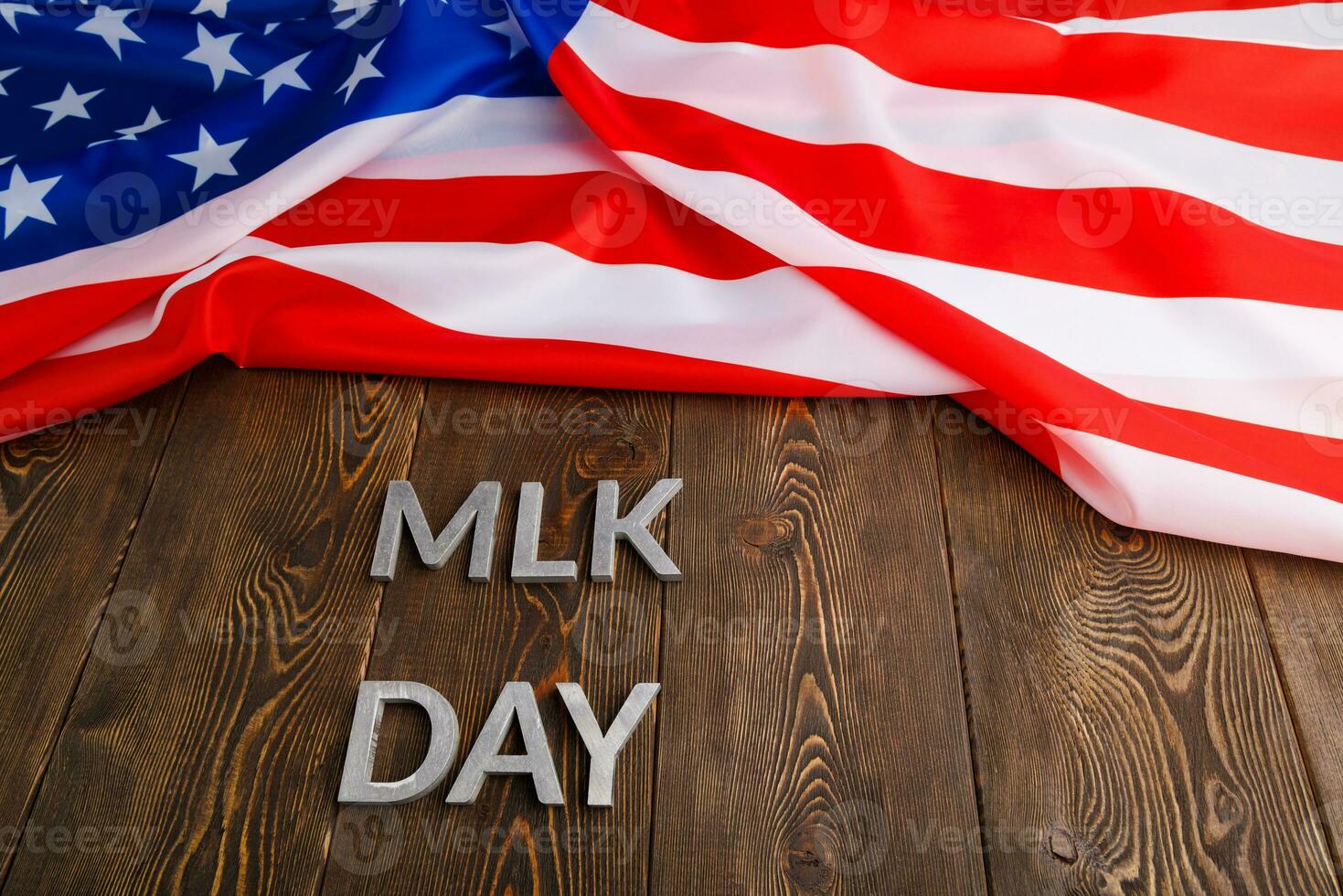 the word MLK day laid with silver metal letters on wooden surface with crumpled USA flag at upper side photo
