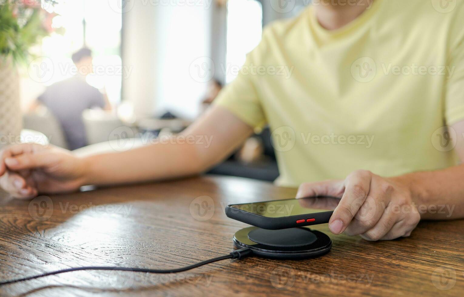 Charging mobile phone battery with wireless charging device in the table. Smartphone charging on a charging pad. Mobile phone near wireless charger Modern lifestyle concept. photo