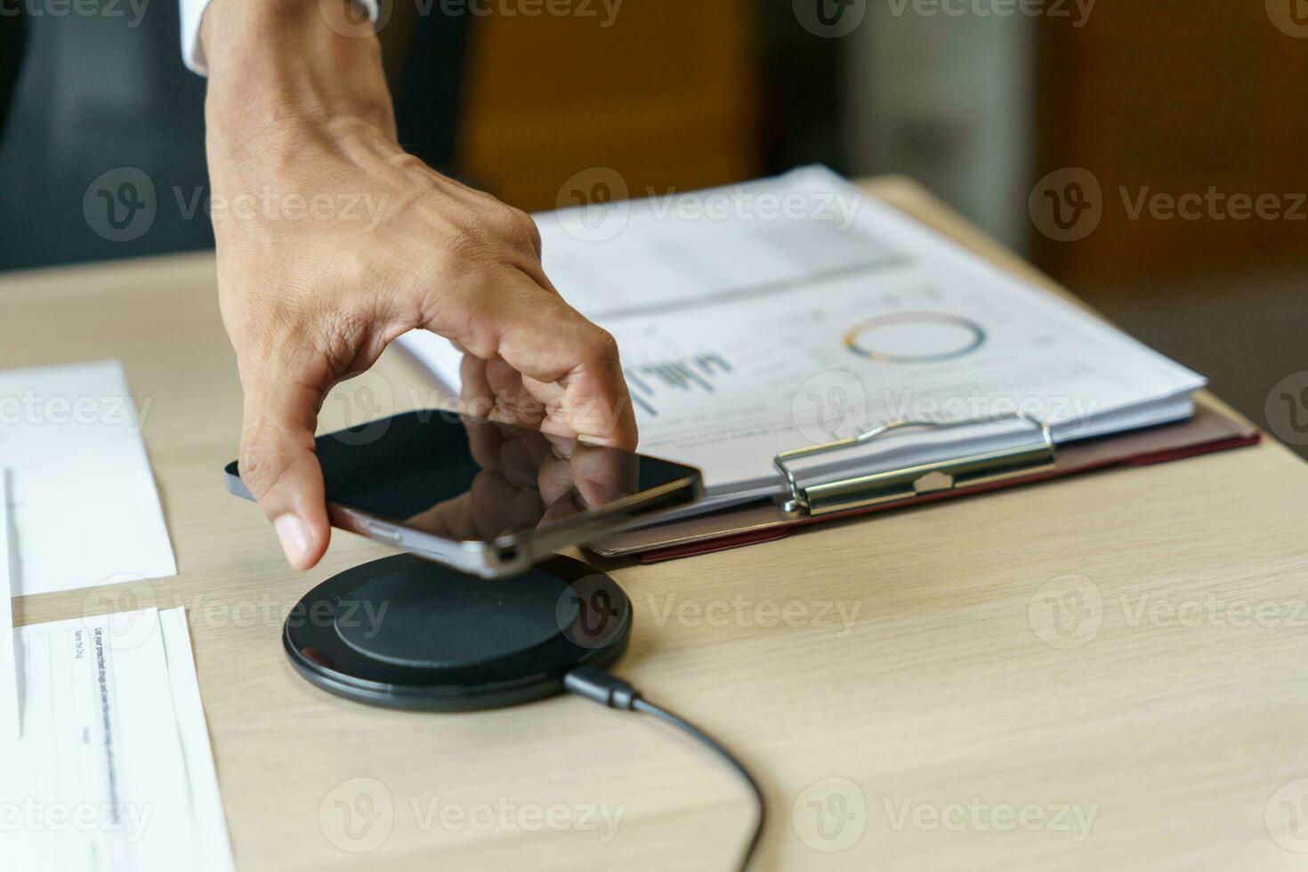 Charging mobile phone battery with wireless charging device in the table. Smartphone charging on a charging pad. Mobile phone near wireless charger Modern lifestyle technology concept photo