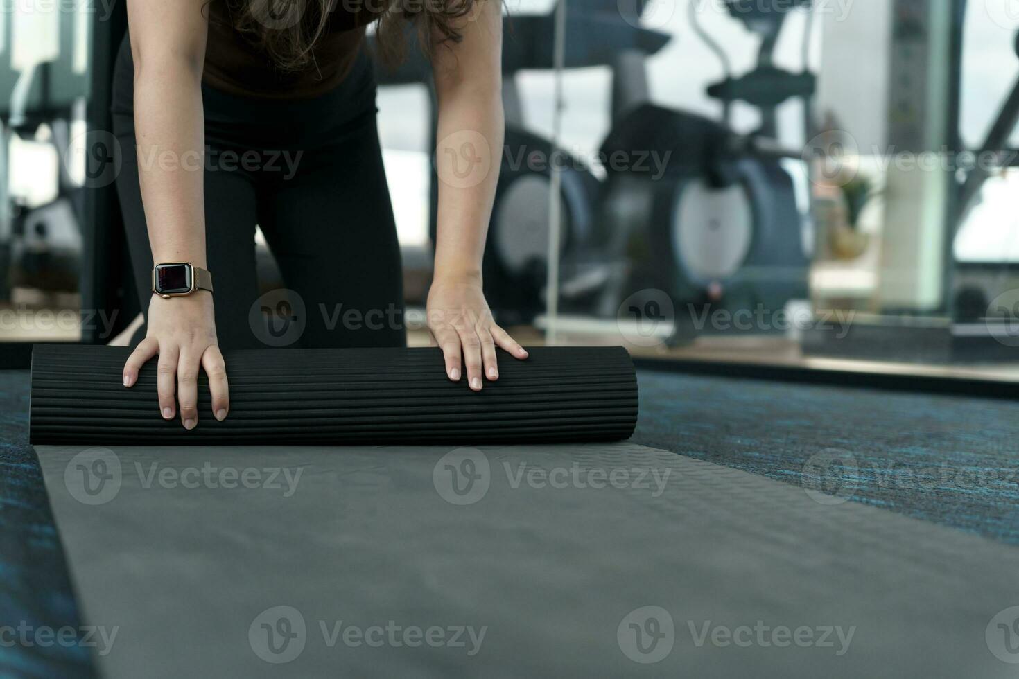 Fitness woman folding exercise mat before working out in yoga studio. rolling Yoga mat  after training healthy lifestyle photo