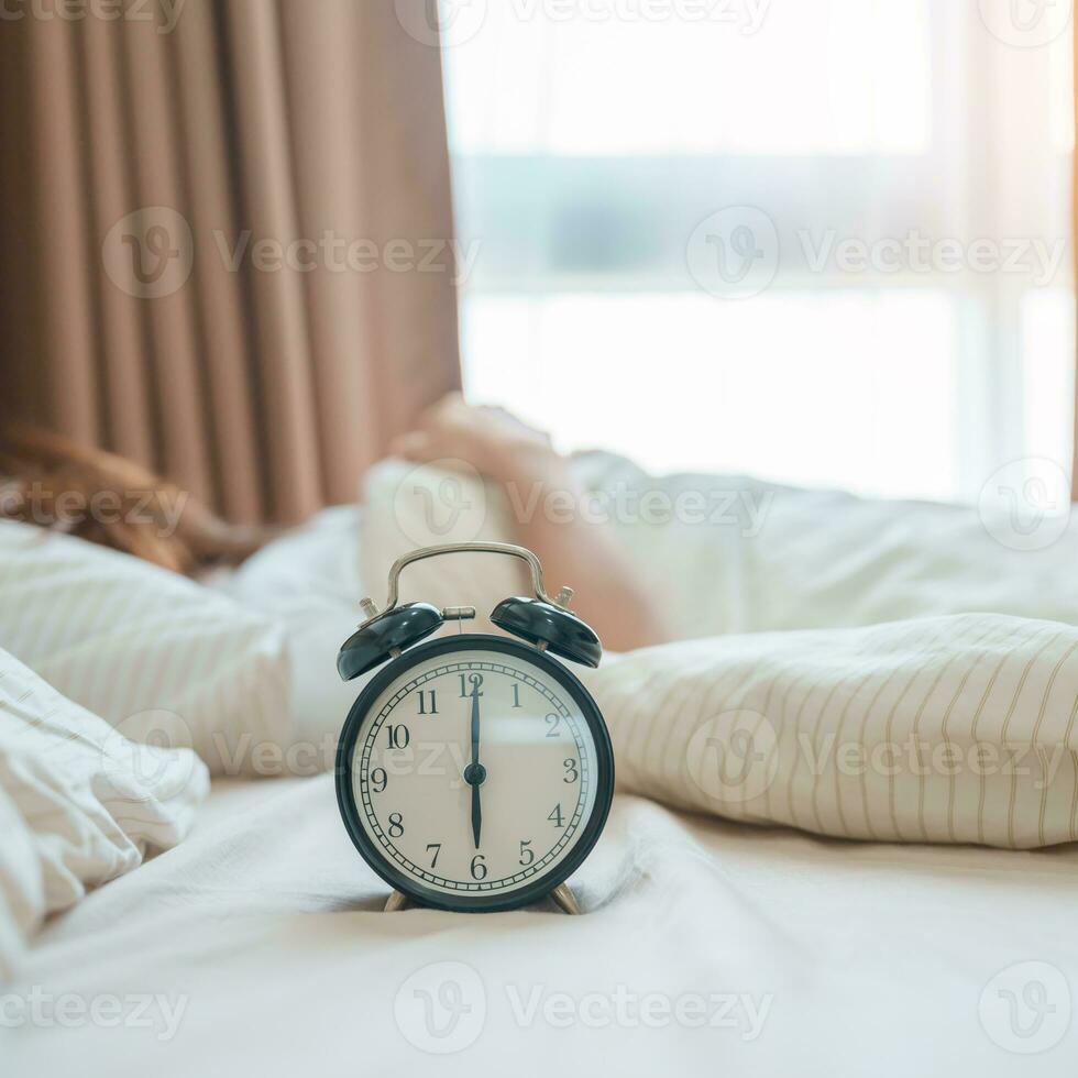 alarm clock with asian woman in bed while sleeping, young adult female wake up late in the early morning. Relaxing , sleepy, daily routine and have a nice day concepts photo