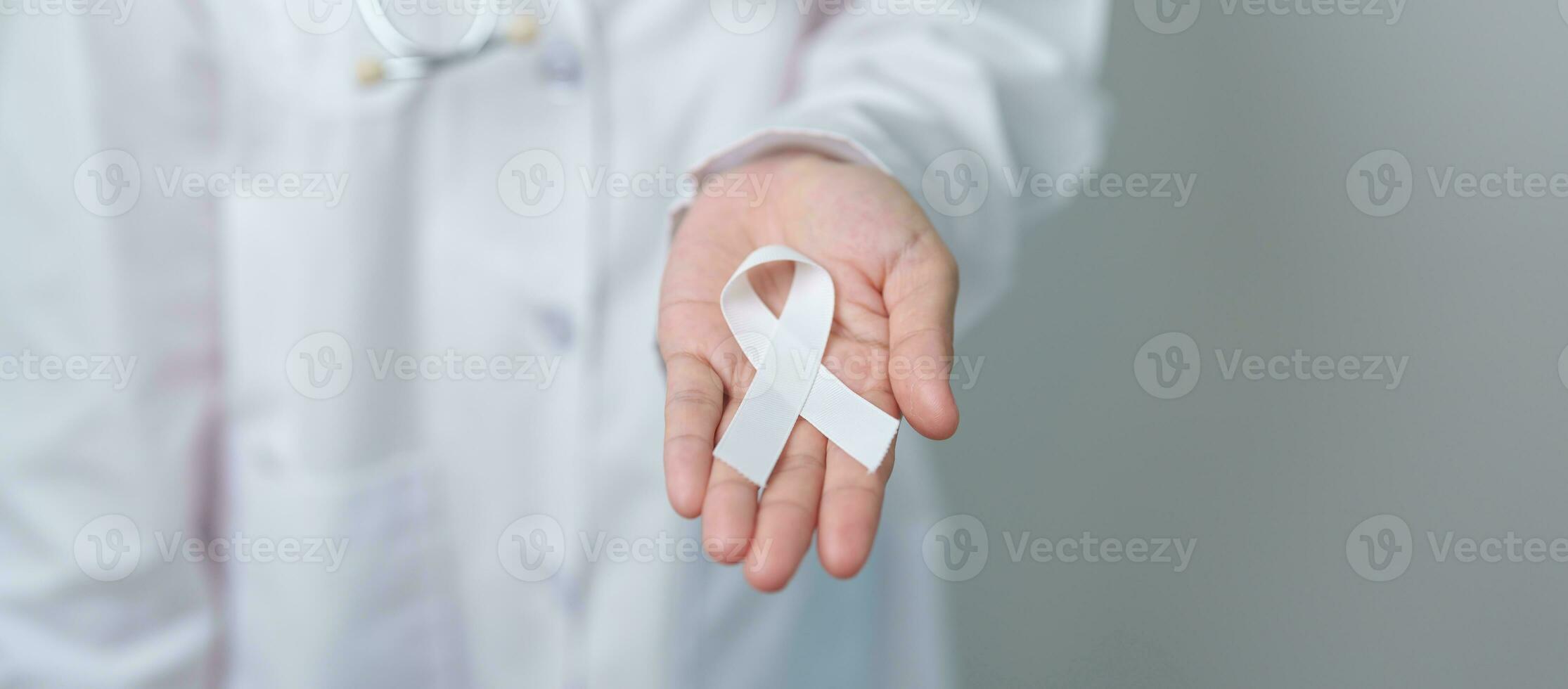 November Lung Cancer Awareness month. Doctor with White ribbon in hospital. Healthcare and World Cancer day concept photo