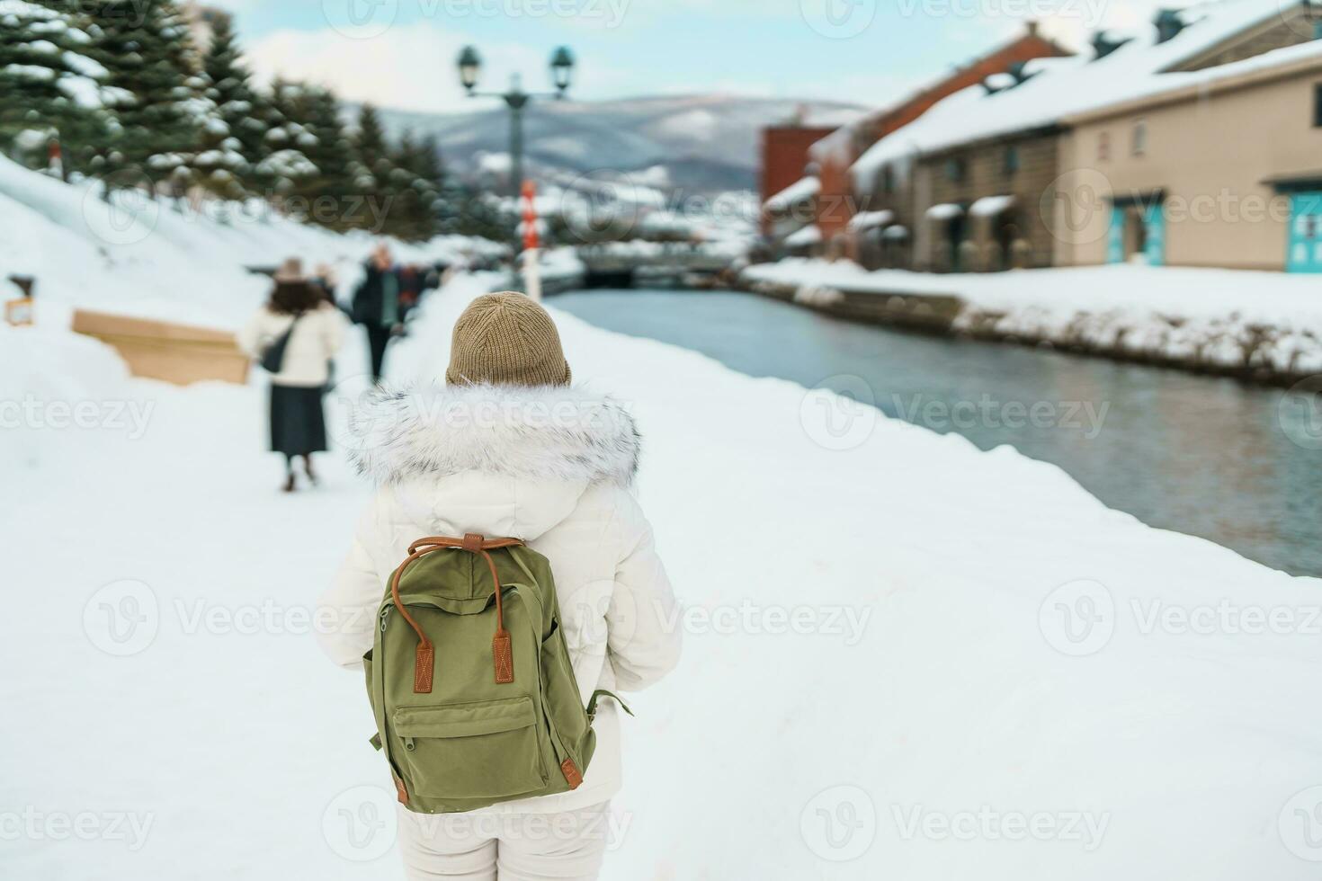 Woman tourist Visiting in Otaru, happy Traveler in Sweater sightseeing Otaru canal with Snow in winter season. landmark and popular for attractions in Hokkaido, Japan. Travel and Vacation concept photo