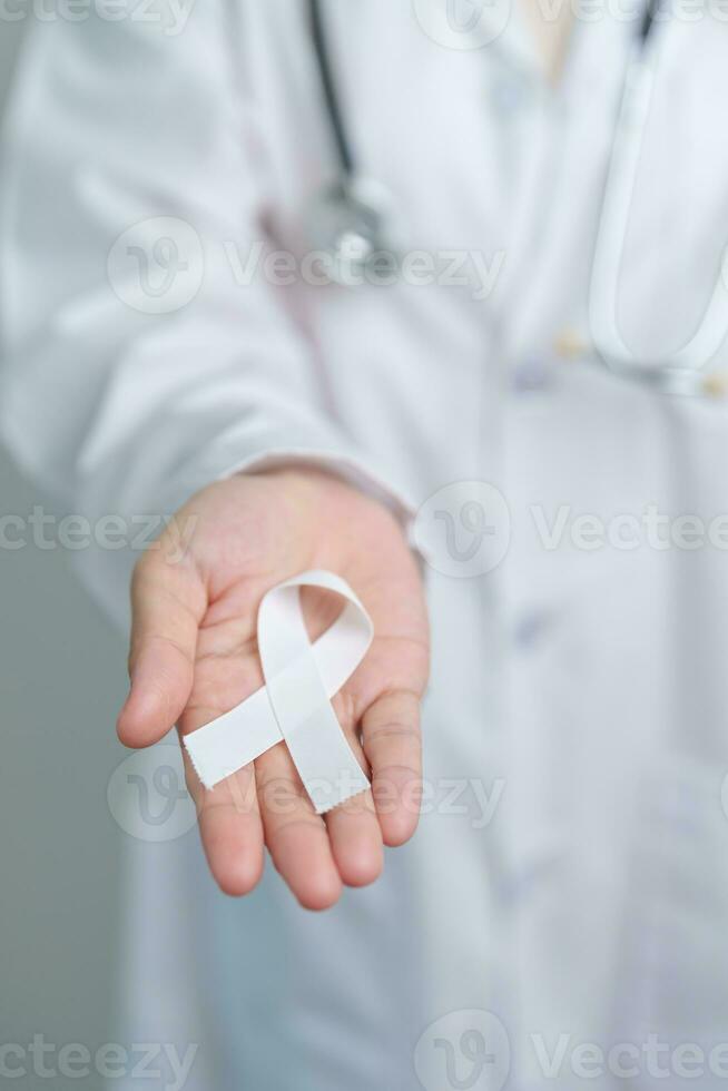 November Lung Cancer Awareness month. Doctor with White ribbon in hospital. Healthcare and World Cancer day concept photo