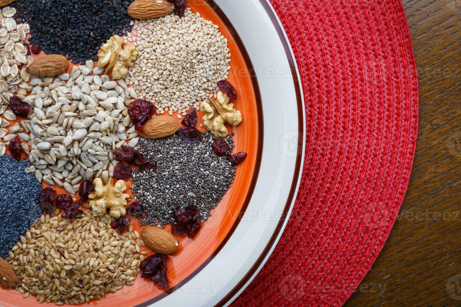 Assortment of fresh dried seeds Used as ingredients in cooking. Sunflower, sesame, linseed, poppy, chia, nuts, rolled oats and Cranberries on plate. photo