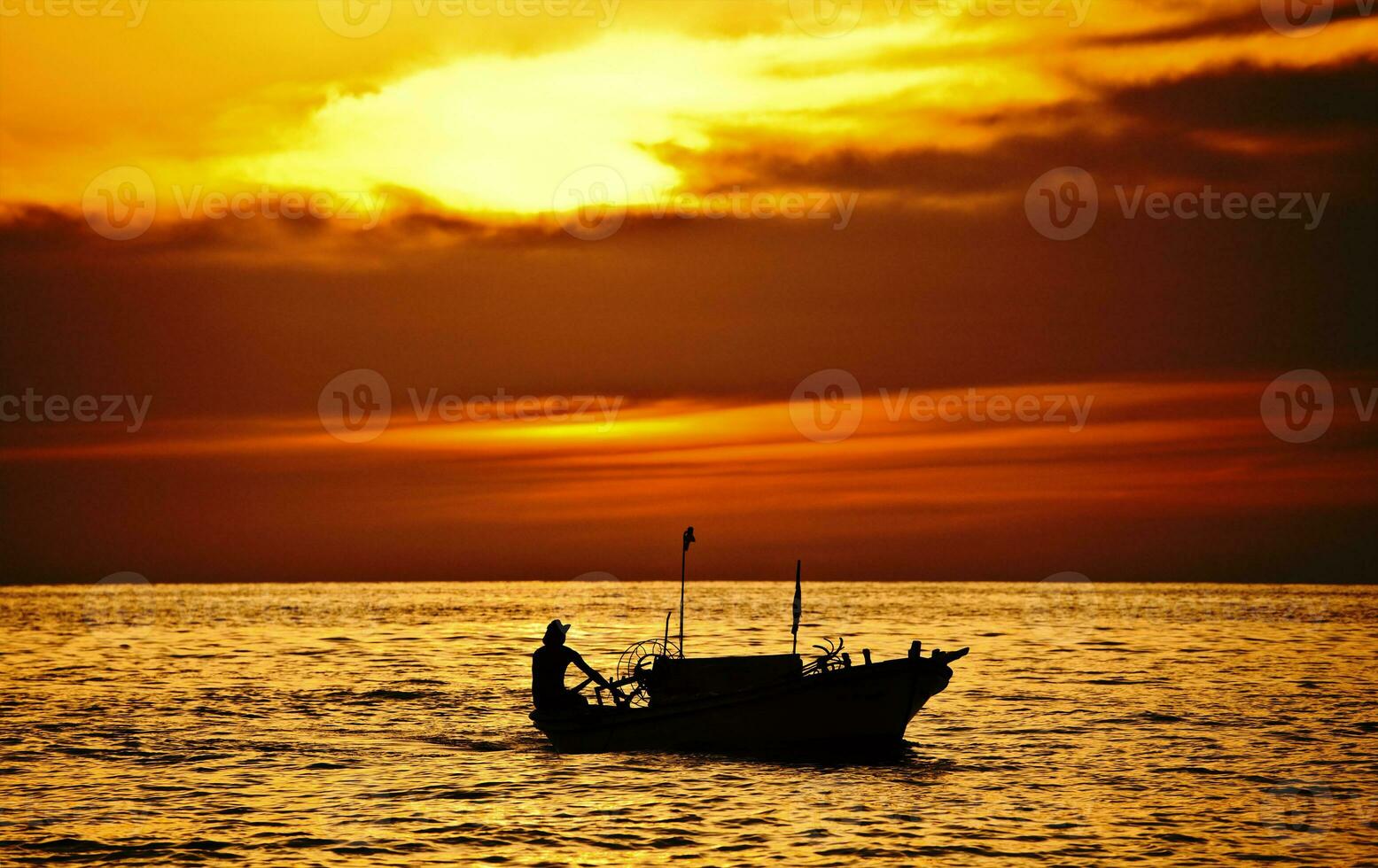 Fisherman on the boat over dramatic sunset photo