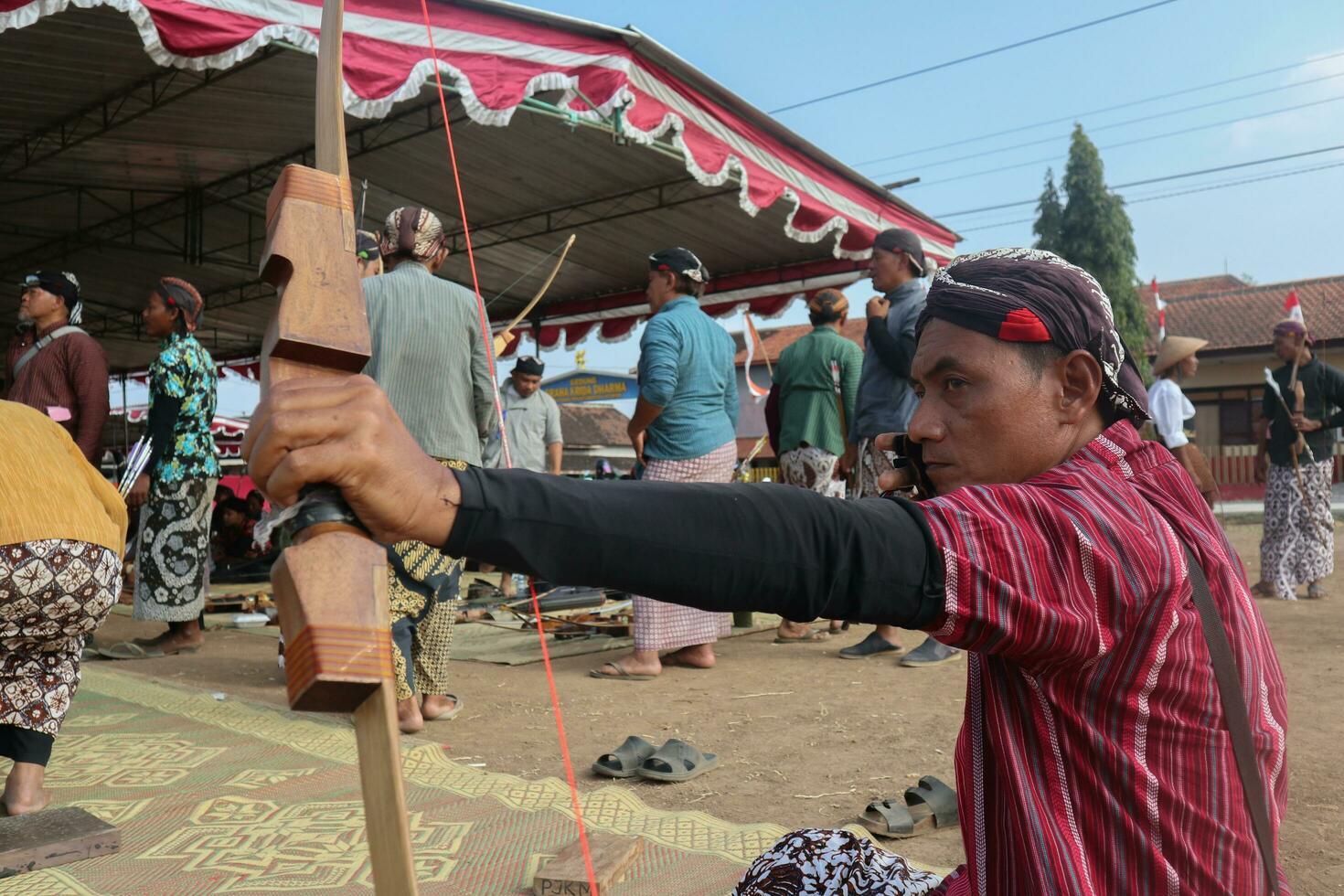 klaten, Indonesia, agosto 15, 2023. masculino y hembra Participantes, vestido en javanés personalizado tirado su arco por bizco a lograr concentración de objetivo exactitud en tradicional javanés flecha comercio. foto