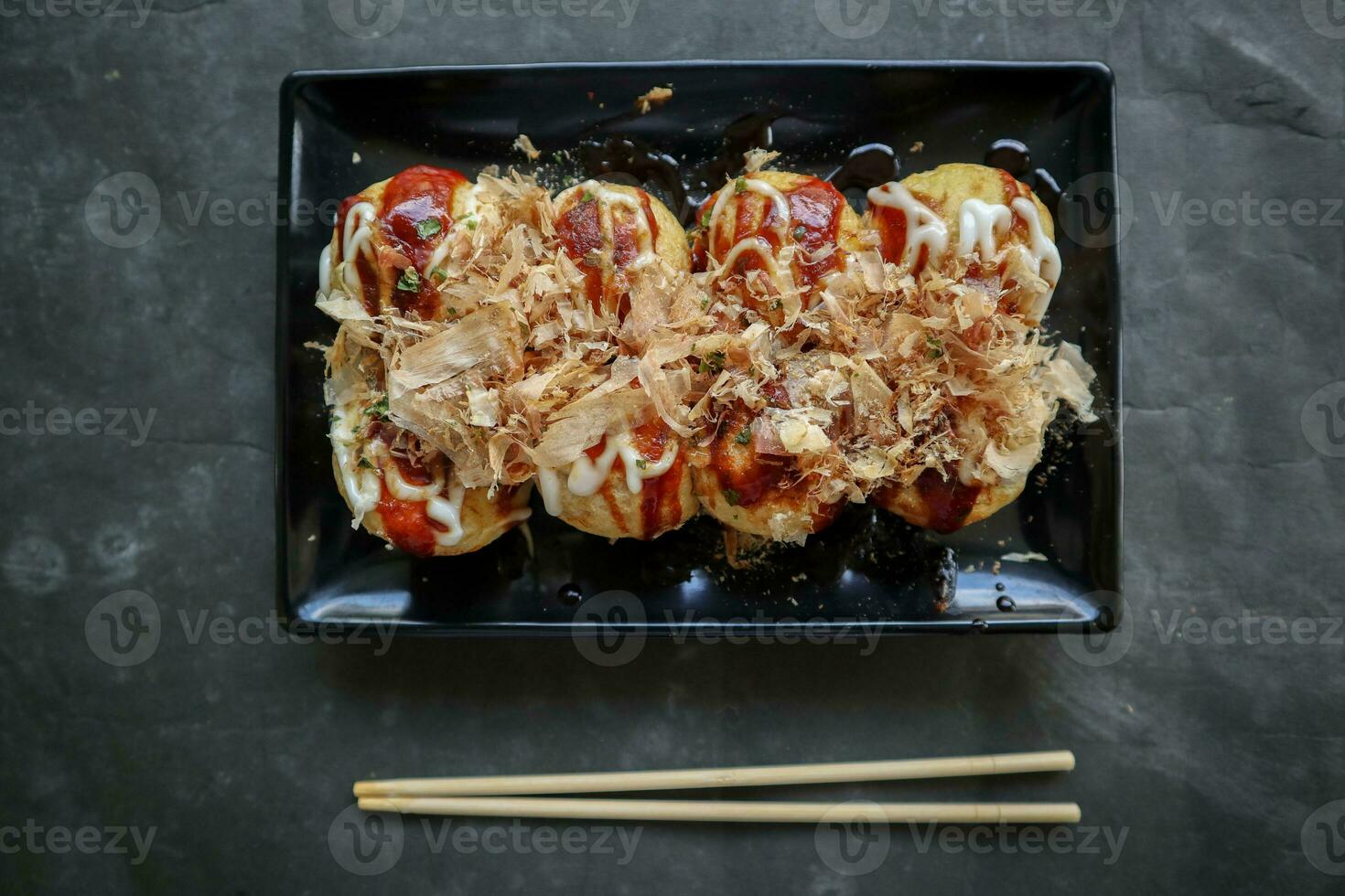 Takoyaki is a Japanese food, made from wheat flour dough, octopus meat, or other fillings, served with sauce, mayonnaise and topping in the form of katsuobushi or wood fish shavings. photo