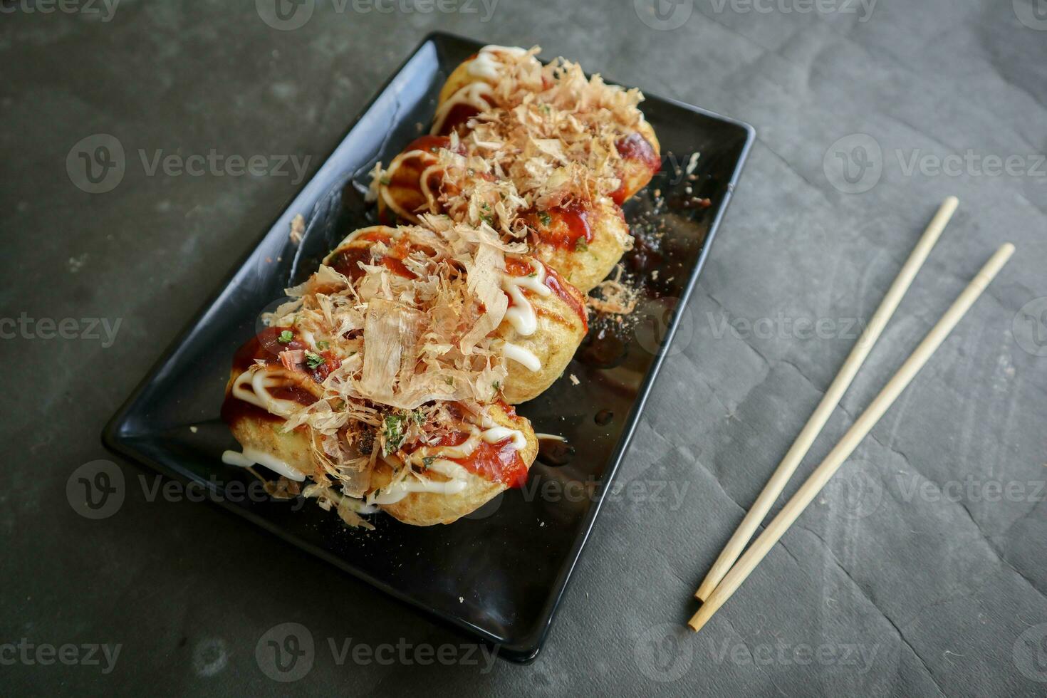 Takoyaki is a Japanese food, made from wheat flour dough, octopus meat, or other fillings, served with sauce, mayonnaise and topping in the form of katsuobushi or wood fish shavings. photo