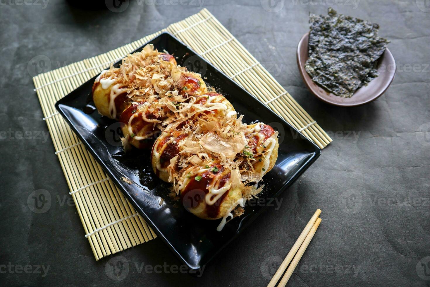 Takoyaki is a Japanese food, made from wheat flour dough, octopus meat, or other fillings, served with sauce, mayonnaise and topping in the form of katsuobushi or wood fish shavings. photo