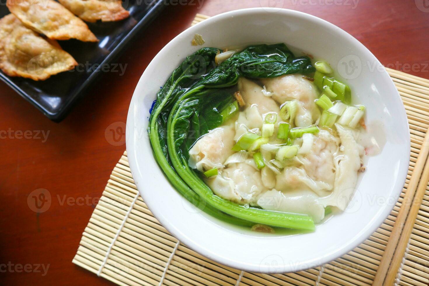 wonton soup. Bowl of wonton soup with chili oil. Shrimp or meat dumpling soup with mustard , green onions, photo