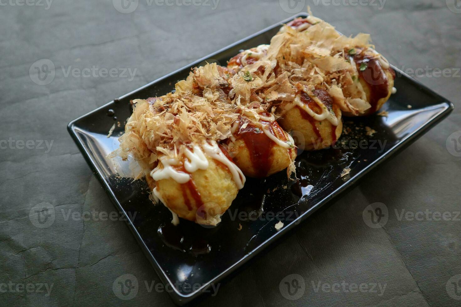 Takoyaki is a Japanese food, made from wheat flour dough, octopus meat, or other fillings, served with sauce, mayonnaise and topping in the form of katsuobushi or wood fish shavings. photo
