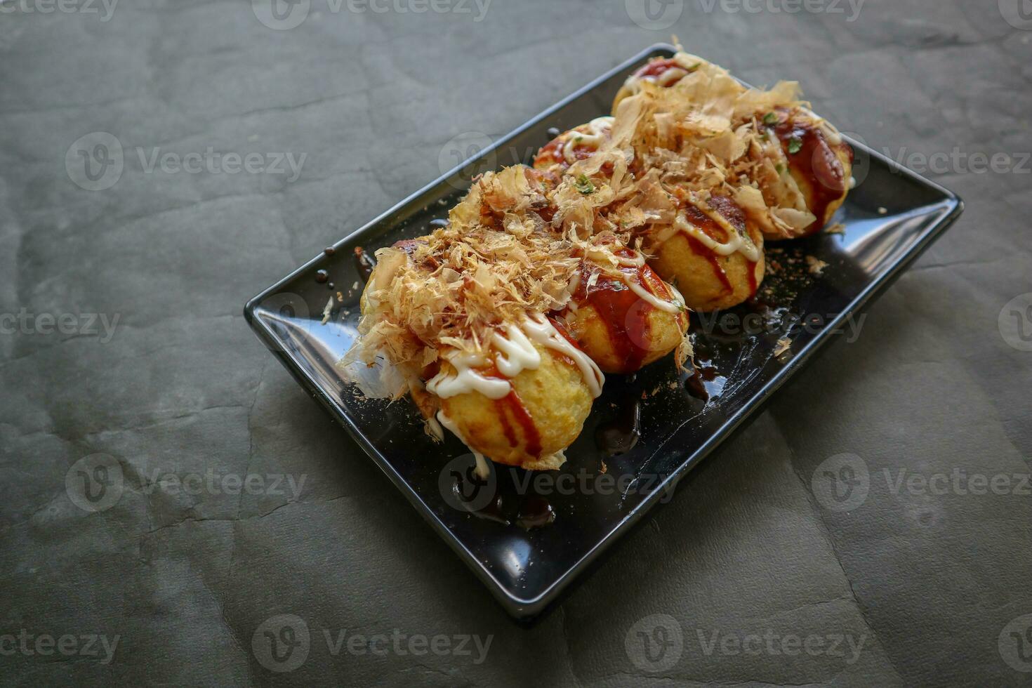 Takoyaki is a Japanese food, made from wheat flour dough, octopus meat, or other fillings, served with sauce, mayonnaise and topping in the form of katsuobushi or wood fish shavings. photo