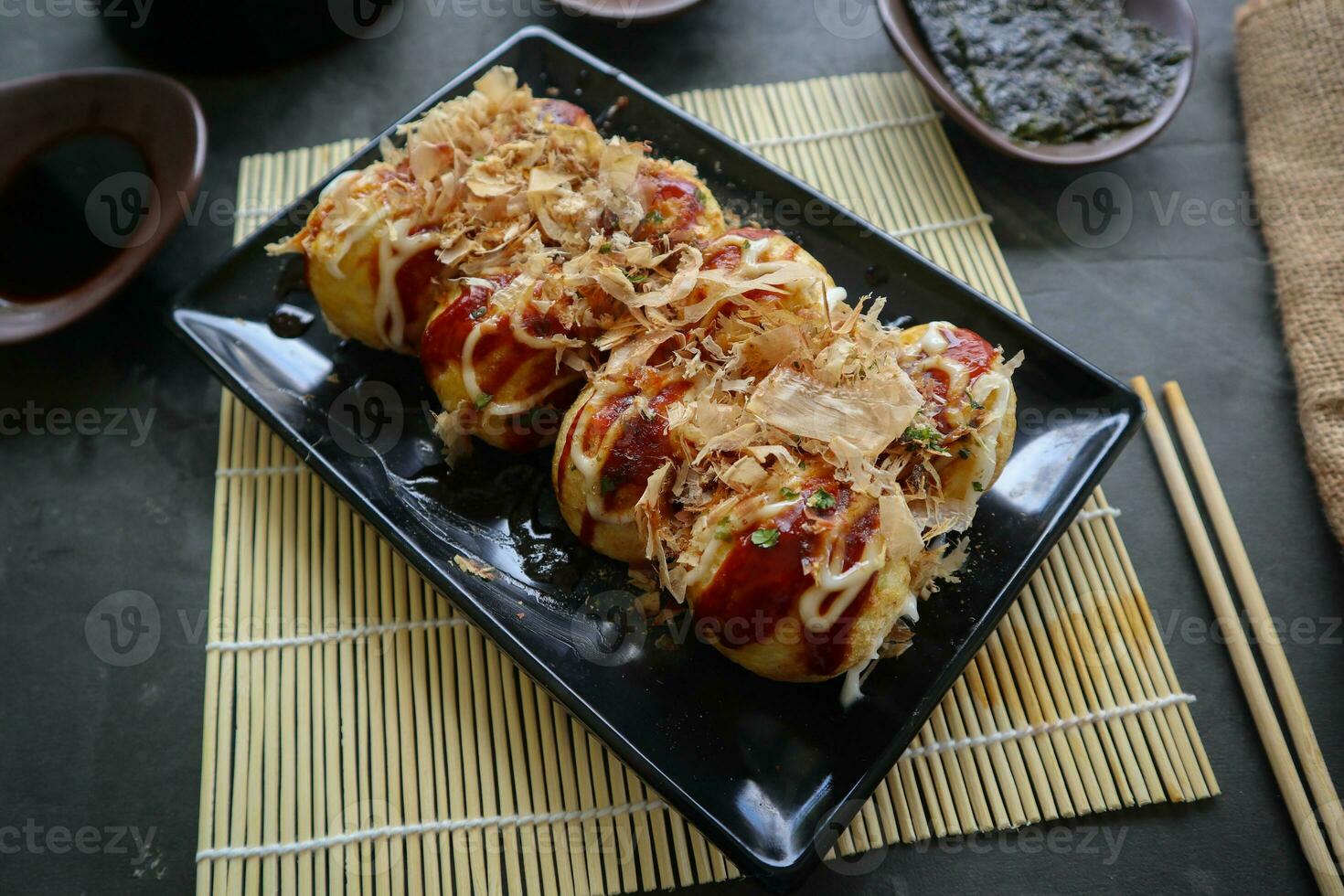 Takoyaki is a Japanese food, made from wheat flour dough, octopus meat, or other fillings, served with sauce, mayonnaise and topping in the form of katsuobushi or wood fish shavings. photo
