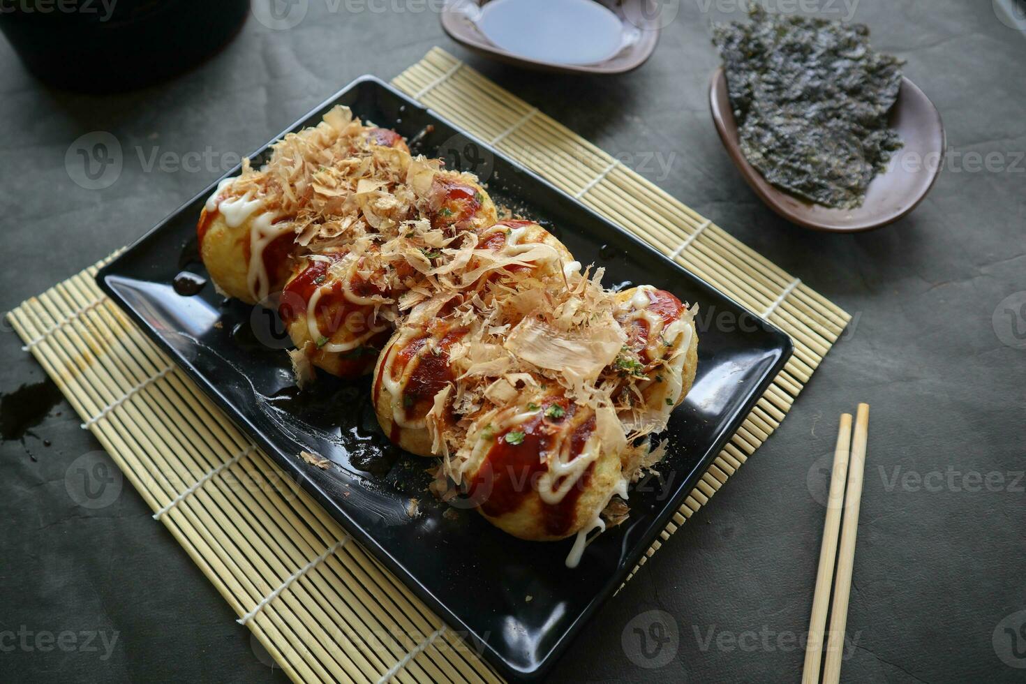 Takoyaki is a Japanese food, made from wheat flour dough, octopus meat, or other fillings, served with sauce, mayonnaise and topping in the form of katsuobushi or wood fish shavings. photo