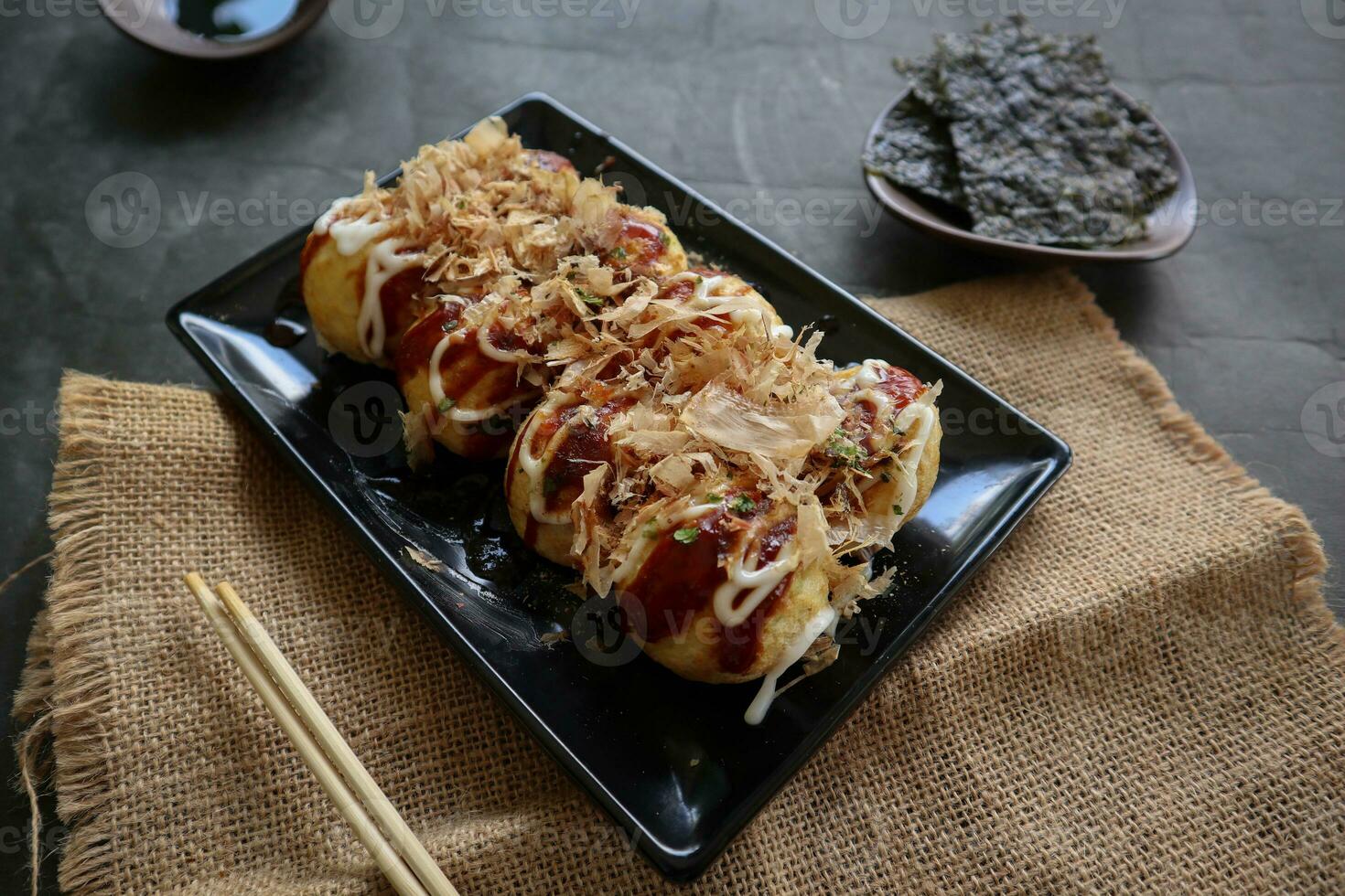 Takoyaki is a Japanese food, made from wheat flour dough, octopus meat, or other fillings, served with sauce, mayonnaise and topping in the form of katsuobushi or wood fish shavings. photo