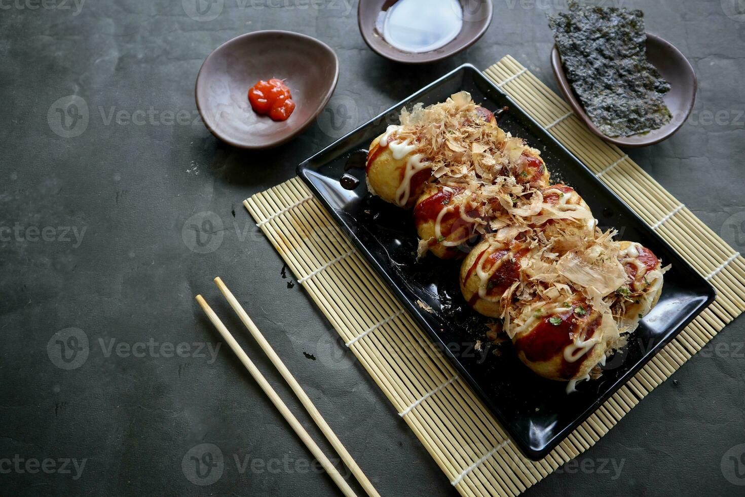 Takoyaki is a Japanese food, made from wheat flour dough, octopus meat, or other fillings, served with sauce, mayonnaise and topping in the form of katsuobushi or wood fish shavings. photo