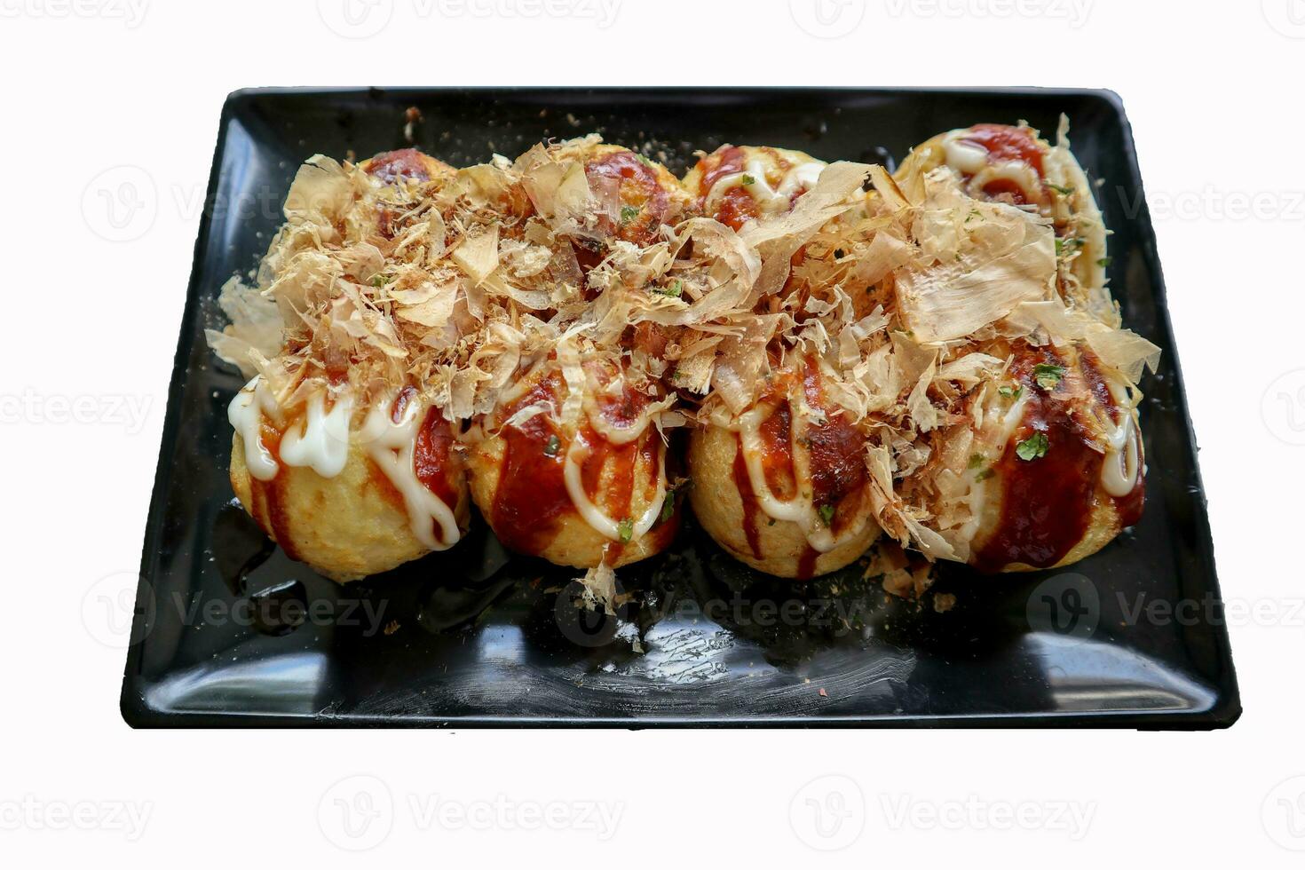 Takoyaki is a Japanese food, made from wheat flour dough, octopus meat, or other fillings, served with sauce, mayonnaise and topping in the form of katsuobushi or wood fish shavings. photo