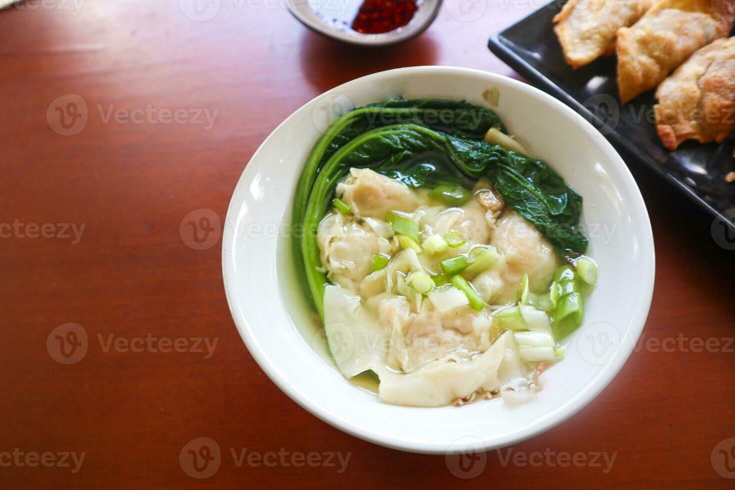 wonton soup. Bowl of wonton soup with chili oil. Shrimp or meat dumpling soup with mustard , green onions, photo