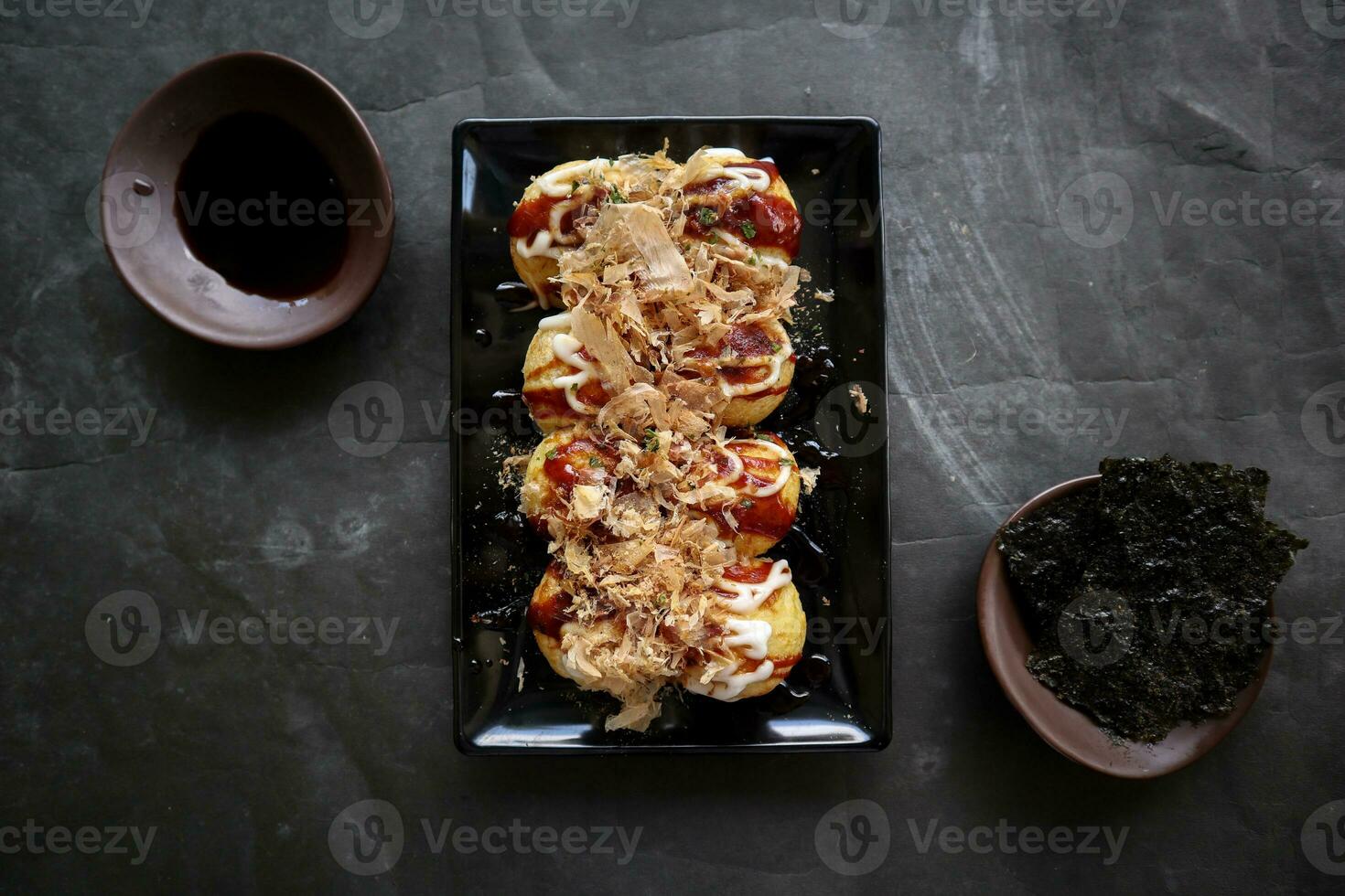 Takoyaki is a Japanese food, made from wheat flour dough, octopus meat, or other fillings, served with sauce, mayonnaise and topping in the form of katsuobushi or wood fish shavings. photo