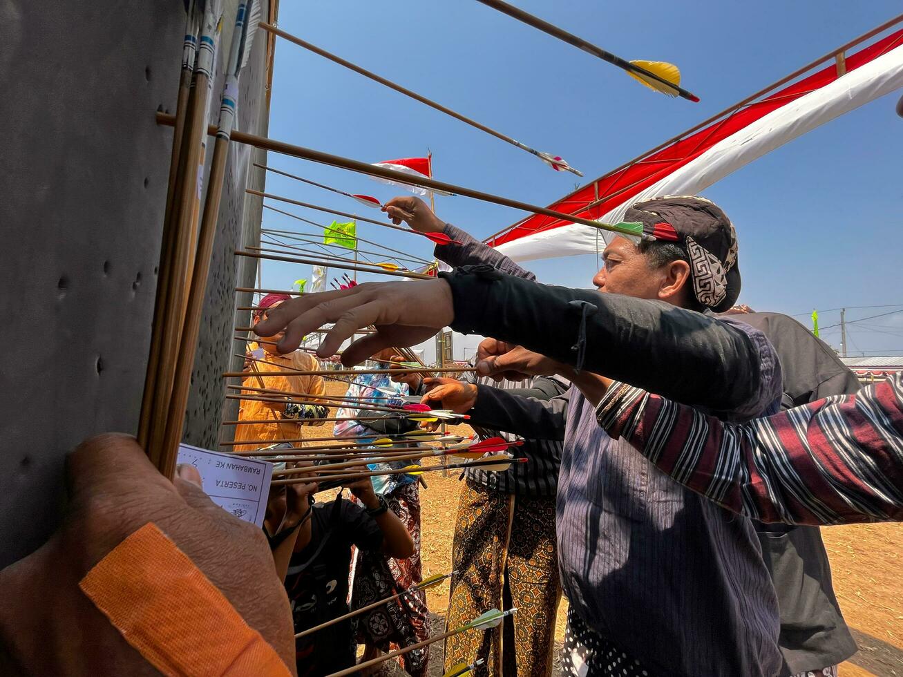 Klaten, Indonesia, august 15, 2023. male and female participants, dressed in Javanese custom pulled his bow by squinting to achieve concentration of target accuracy in traditional Javanese arrow trad. photo