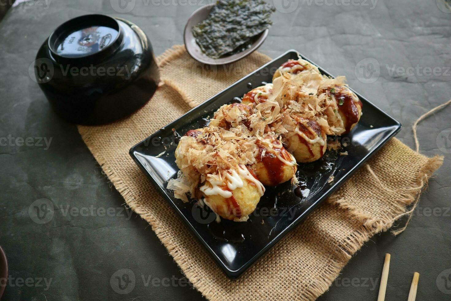 Takoyaki is a Japanese food, made from wheat flour dough, octopus meat, or other fillings, served with sauce, mayonnaise and topping in the form of katsuobushi or wood fish shavings. photo