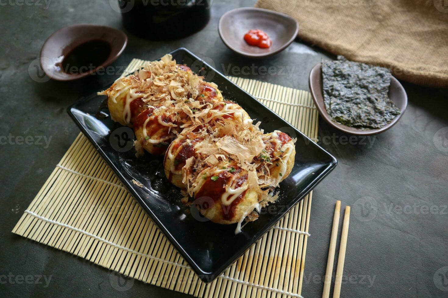 Takoyaki is a Japanese food, made from wheat flour dough, octopus meat, or other fillings, served with sauce, mayonnaise and topping in the form of katsuobushi or wood fish shavings. photo