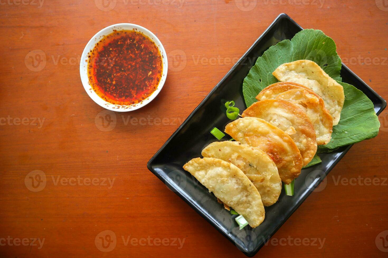 fried wonton. wonton on plate with chili oil. Shrimp or meat dumpling soup with mustard , green onions, on table photo