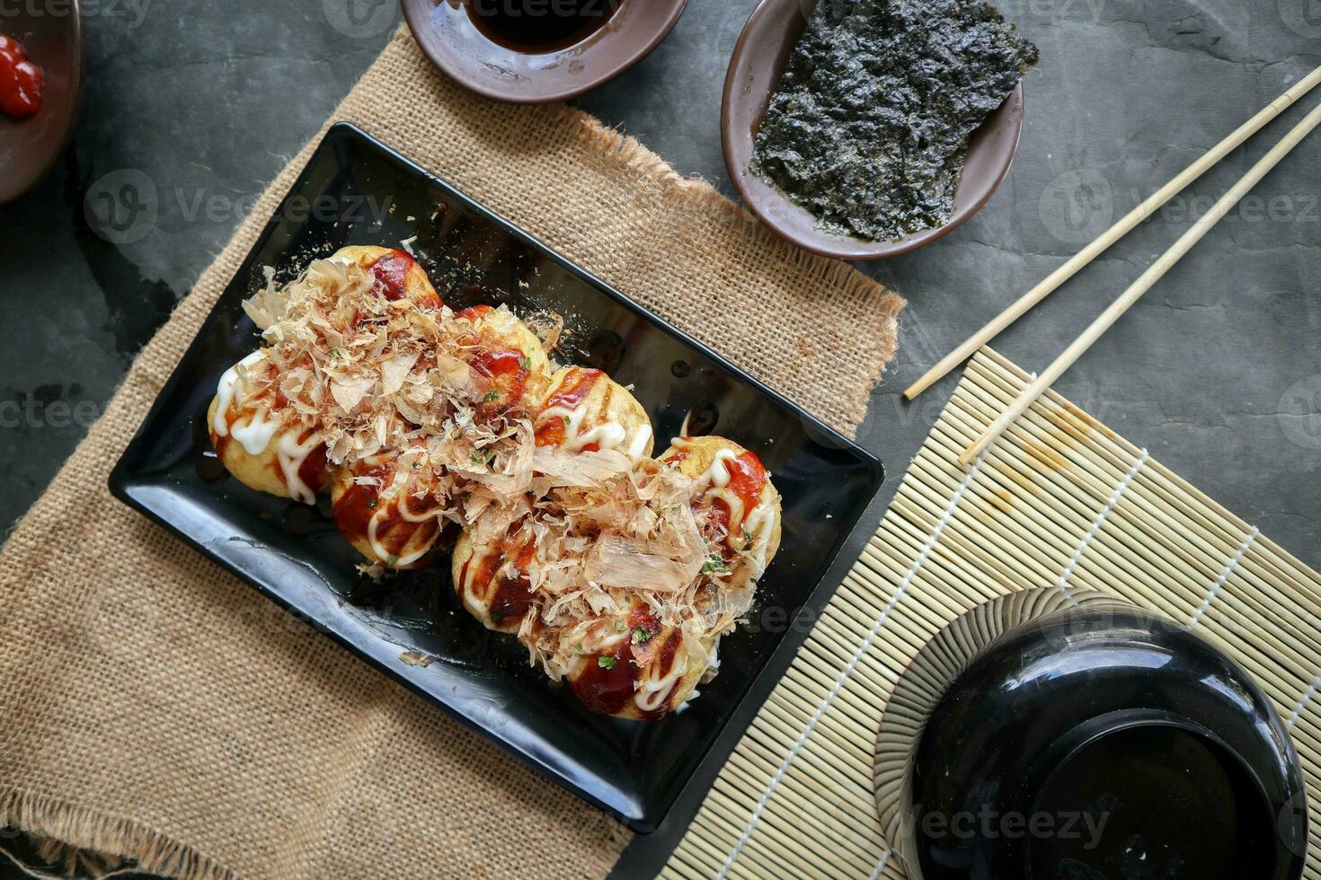 Takoyaki is a Japanese food, made from wheat flour dough, octopus meat, or other fillings, served with sauce, mayonnaise and topping in the form of katsuobushi or wood fish shavings. photo