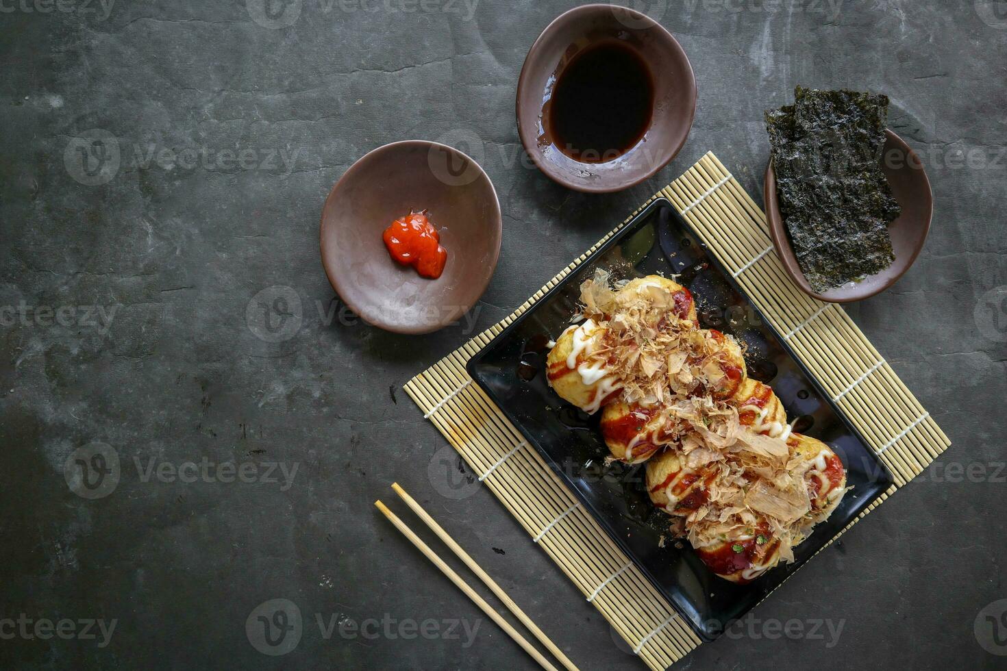 Takoyaki is a Japanese food, made from wheat flour dough, octopus meat, or other fillings, served with sauce, mayonnaise and topping in the form of katsuobushi or wood fish shavings. photo