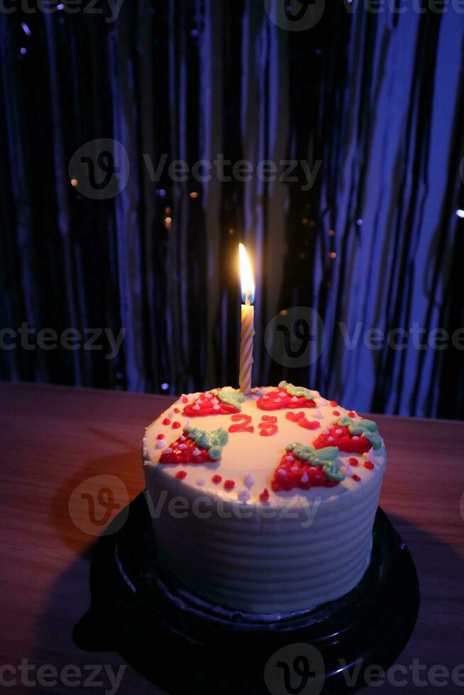 birthday cake with sprinkles strawberry and one candles on a blue background photo