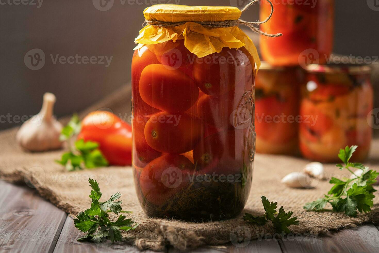 Homemade jars of pickled tomatoes on a rustic wooden background. Pickled and canned product. Next other for cooking photo