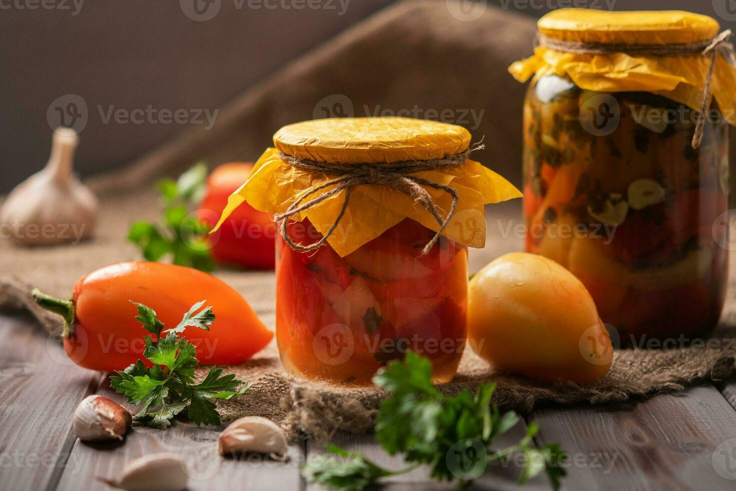 Homemade jars of pickled peppers on a rustic wooden background. Pickled and canned product. Next other for cooking photo