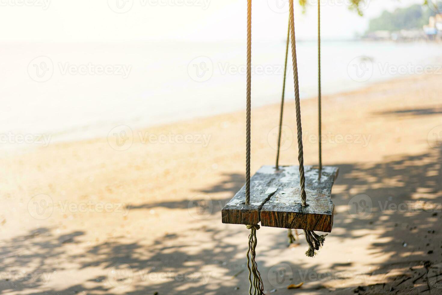 Wooden swing on the beach on a tropical beach against the sun light, relaxing by the sea tropical climate in Thailand summer photo