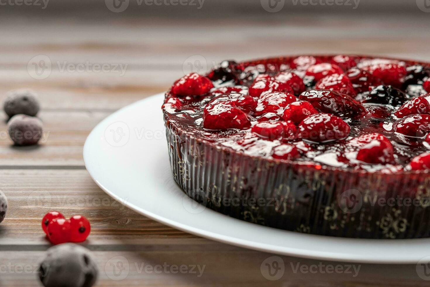 Pie with berries closeup, raspberry, currant, strawberry on a white plate on a wooden background, near red currant and cherry photo