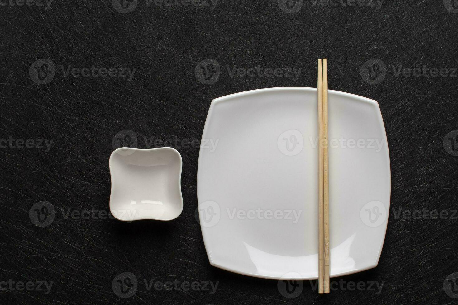 Empty white plate with chopsticks and a gravy boat on a dark background. Japanese food style. Top view with copy space photo